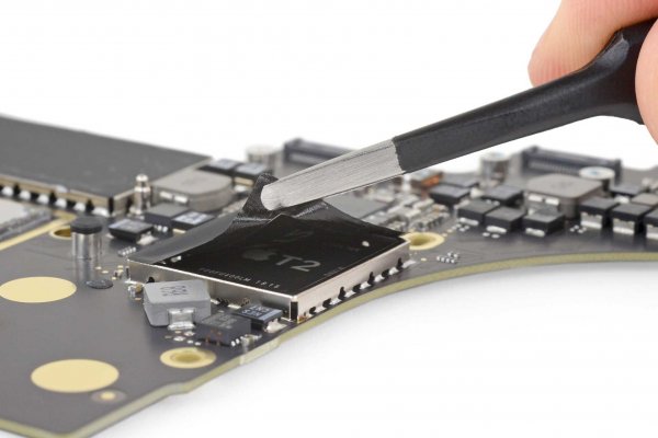 Tweezers peeling the cover off a T2 security chip